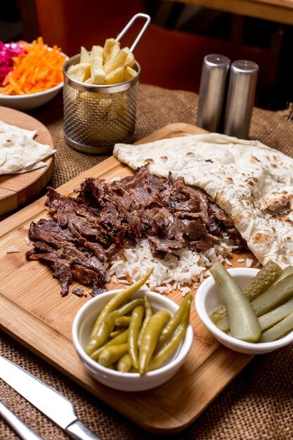Doner kebab de cordero servido sobre arroz con pan plano y encurtidos