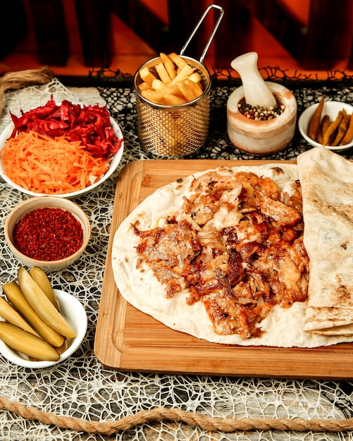 Doner kebab de pollo servido en pan plano con papas fritas y encurtidos