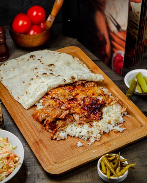 Doner de pollo con arroz sobre tabla de madera