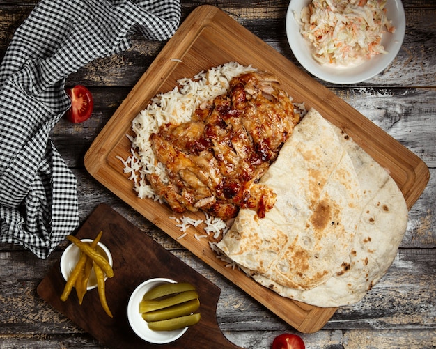 Doner de pollo frito con arroz sobre tabla de madera