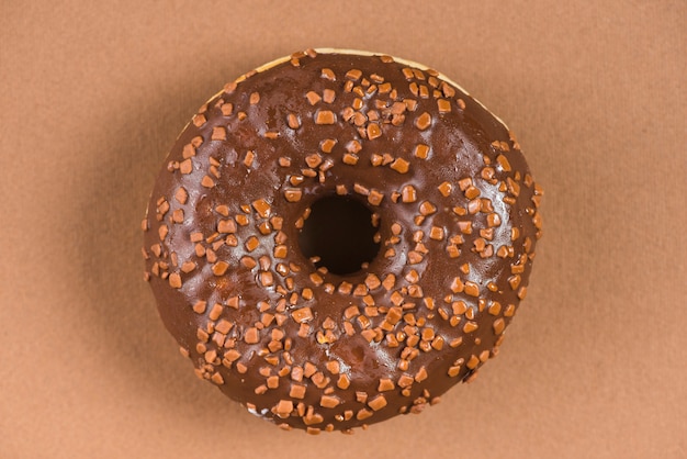 Donut de chocolate oscuro con salpicaduras sobre fondo marrón