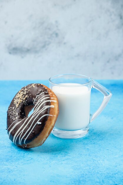 Donut de chocolate con un vaso de leche en el cuadro azul.