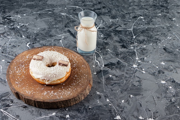 Donut de coco delicioso con chocolate y vaso de leche en la mesa de mármol.