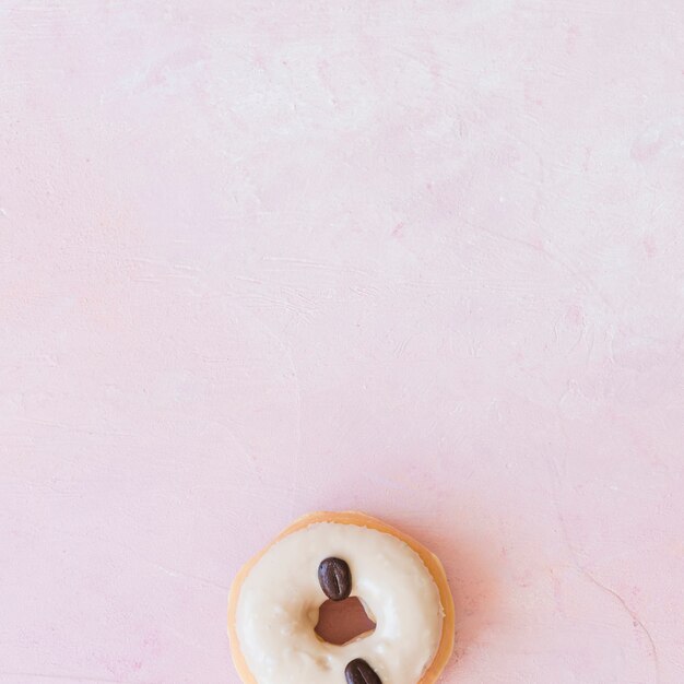 Donut decorado con granos de café en el fondo de fondo rosa