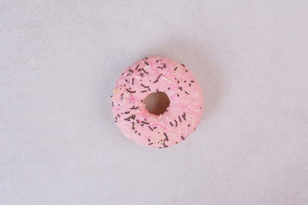 Donut dulce rosa sobre superficie blanca