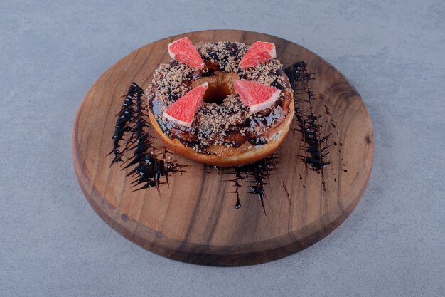 Donut fresco con rodajas de pomelo sobre tabla de madera