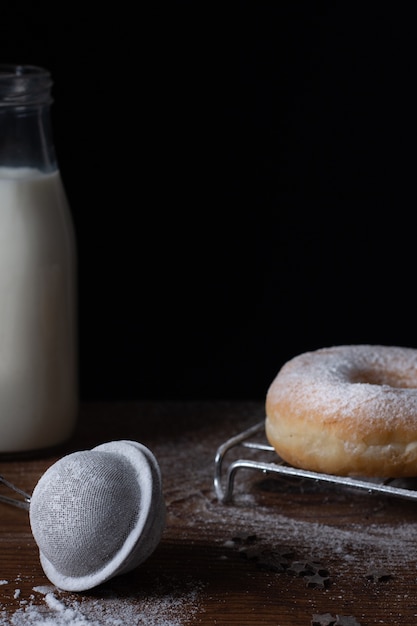 Donut con glaseado de azúcar en polvo y botella de leche