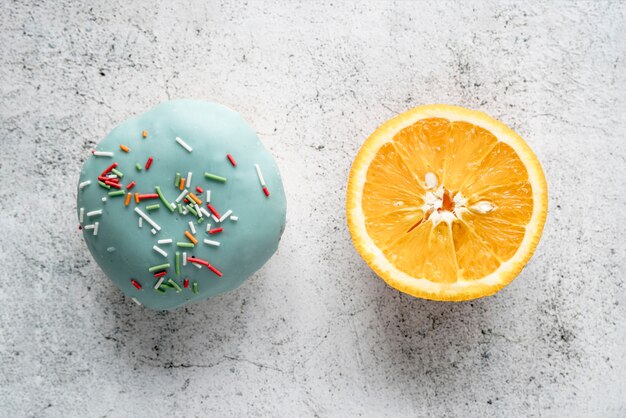 Donut glaseado y naranja a la mitad sobre fondo de hormigón