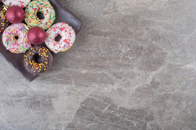 Donuts y adornos navideños dispuestos en una bandeja sobre la superficie de mármol
