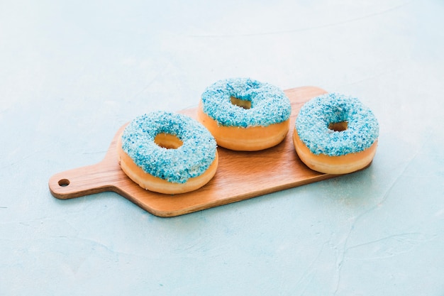 Donuts azules sabrosos en tabla de cortar de madera