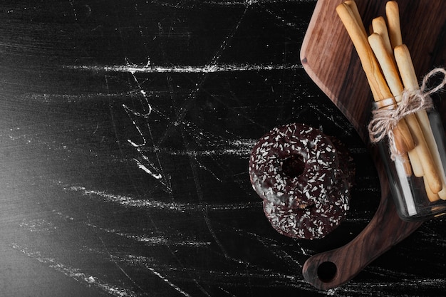 Donuts de chocolate en una bandeja de madera con palos de gofres.