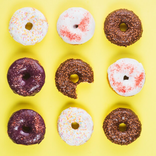 Donuts de chocolate blanco y marrón con chispas y mordida faltante