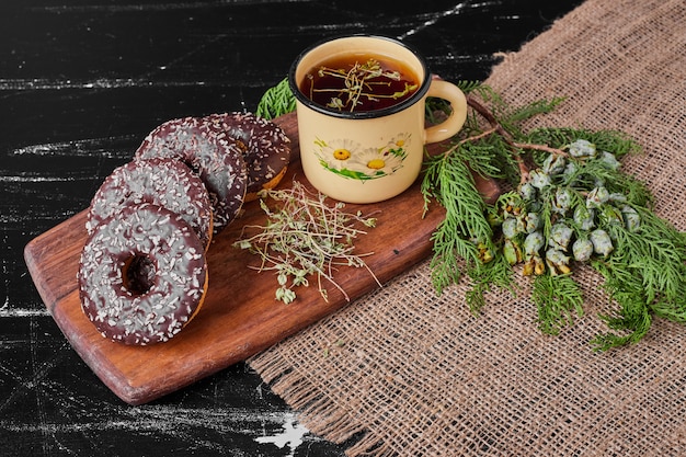 Donuts de chocolate en un plato de madera con té de hierbas.