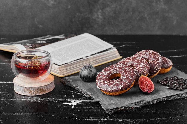 Donuts de chocolate sobre una placa de piedra con té.