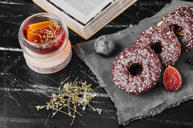 Donuts de chocolate sobre una placa de piedra con té.