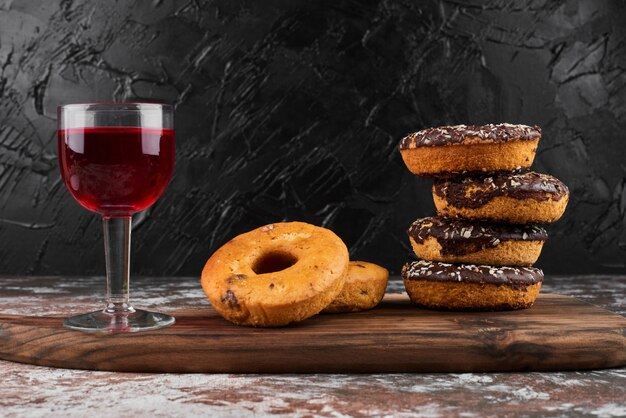 Donuts de chocolate sobre una tabla de madera con una copa de vino.
