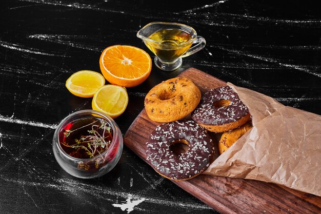 Donuts de chocolate sobre una tabla de madera con té de hierbas