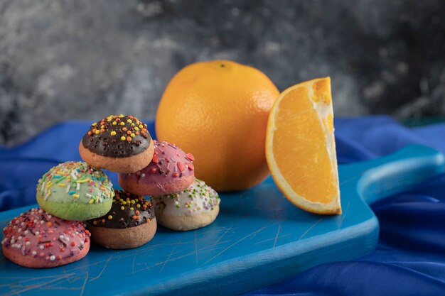 Donuts dulces coloridos con rodajas de naranja.