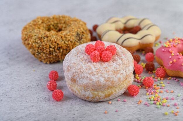 Donuts espolvoreados con azúcar glas y dulces sobre una superficie blanca.