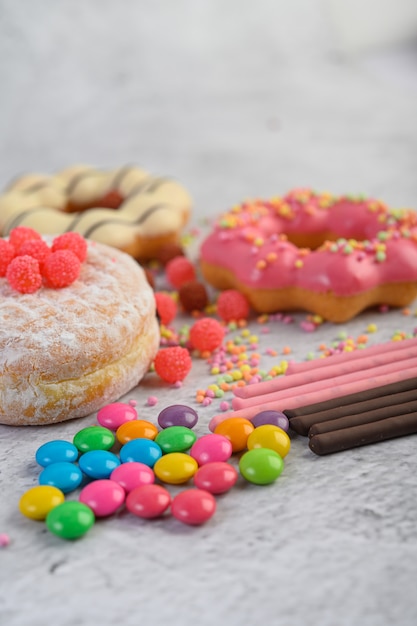 Donuts espolvoreados con azúcar glas y dulces sobre una superficie blanca.