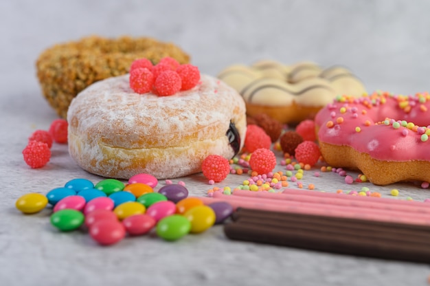 Donuts espolvoreados con azúcar glas y dulces sobre una superficie blanca.
