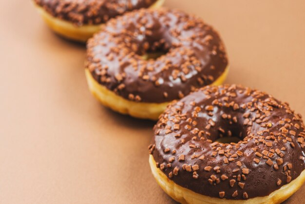Donuts de glaseado de chocolate oscuro sobre fondo marrón