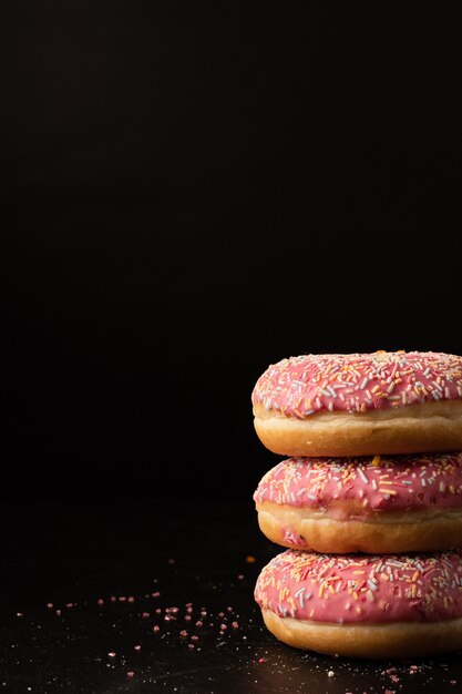 Donuts glaseados apilados con chispas y espacio de copia