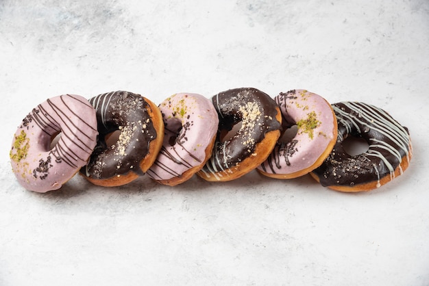 Foto gratuita donuts glaseados de chocolate y rosa sobre superficie blanca.