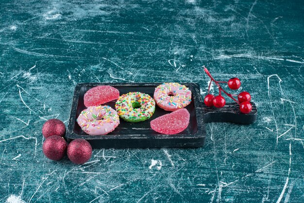 Donuts y mermeladas en un plato pequeño junto a adornos navideños en azul.