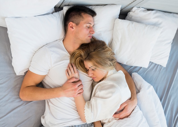 Foto gratuita dormir joven pareja abrazándose en la cama