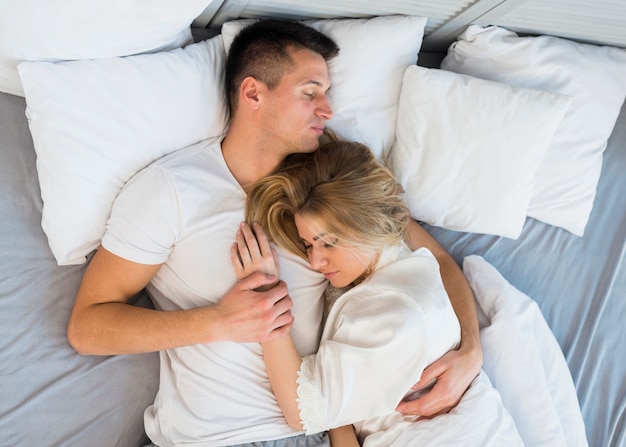 Dormir joven pareja abrazándose en la cama