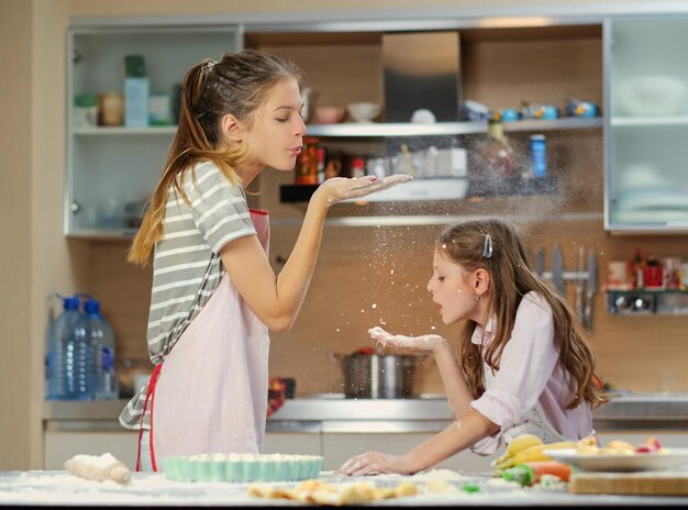 Dos adolescentes divirtiéndose en la cocina al hacer la masa.