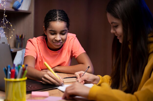 Dos adolescentes estudiando juntas en casa con una laptop