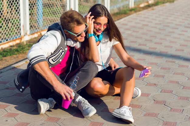 Dos adolescentes modernos bastante jóvenes posando al aire libre en elegante traje casual