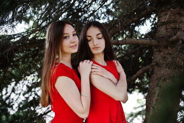 Foto gratuita dos adolescentes vestidas de azul y rojo posaron al aire libre y abrazadas