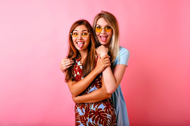 Dos adorables mujeres jóvenes felices divirtiéndose juntos mostrando lenguas