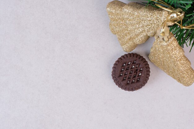 Dos adornos navideños dorados con cookie sobre superficie blanca