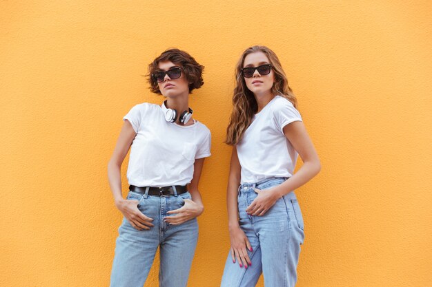 Dos alegres jóvenes adolescentes en gafas de sol posando