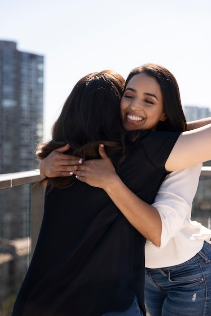 Dos amigas abrazándose después de verse en una terraza en la azotea