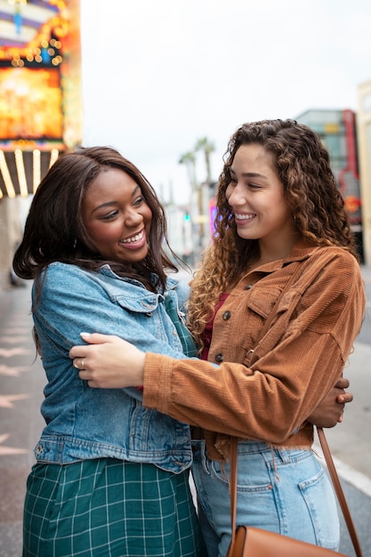 Foto gratuita dos amigas abrazándose mientras están en la ciudad