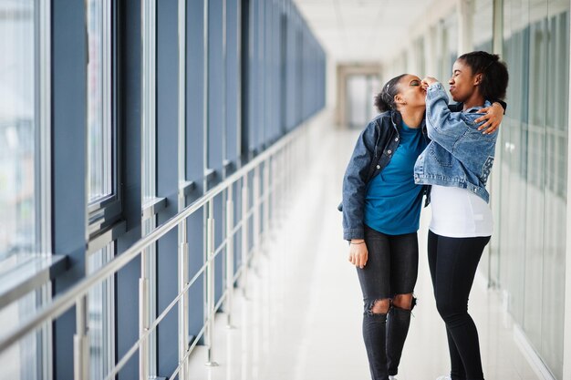 Dos amigas africanas con chaqueta de jeans atrapan la nariz en el interior juntas