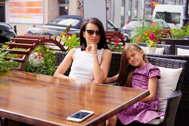Dos amigas atractivas posando en la mesa en un café al aire libre.