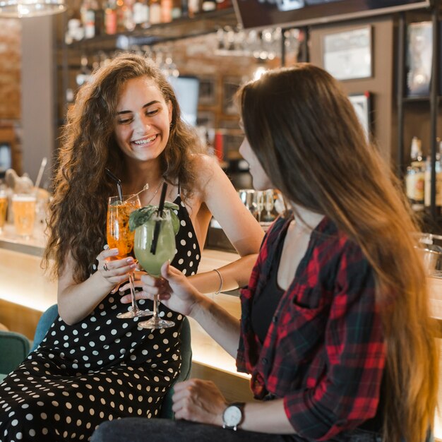 Dos amigas brindando cócteles vasos en la barra