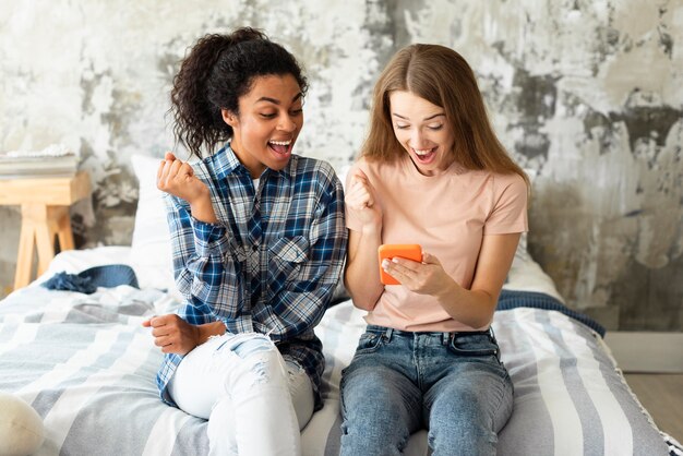 Dos amigas en la cama mirando smartphone