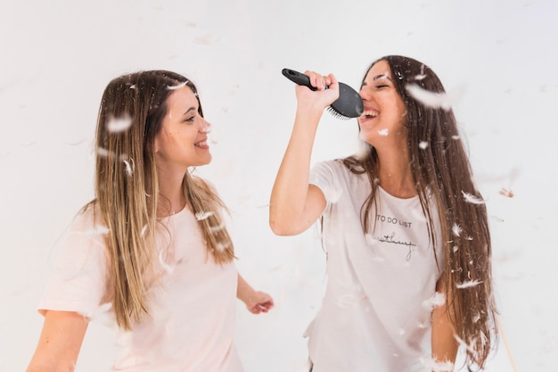 Dos amigas cantan y se divierten con plumas en el aire