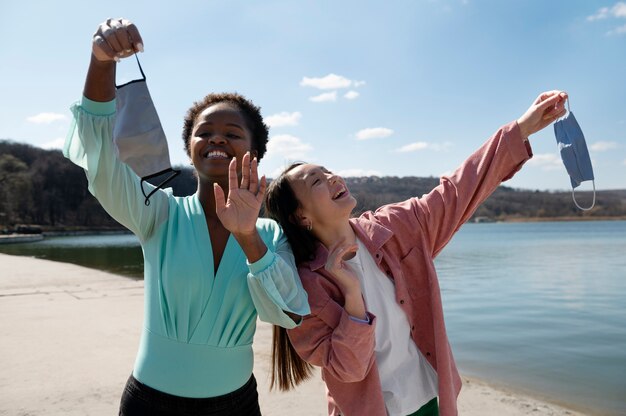 Dos amigas celebrando juntas el levantamiento de las restricciones de mascarillas al aire libre