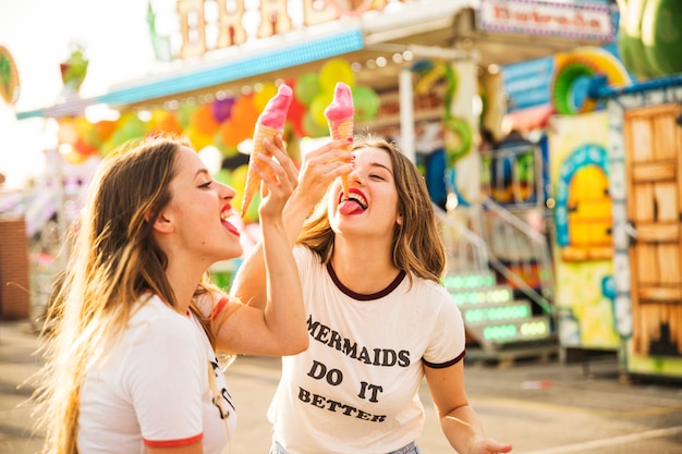 Dos amigas comiendo un helado en el parque de atracciones