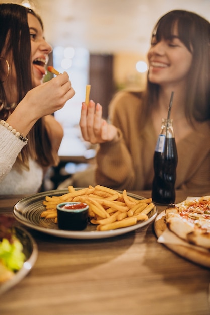 Dos amigas comiendo pizza en un café