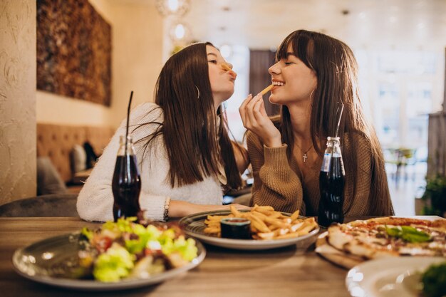 Dos amigas comiendo pizza en un café