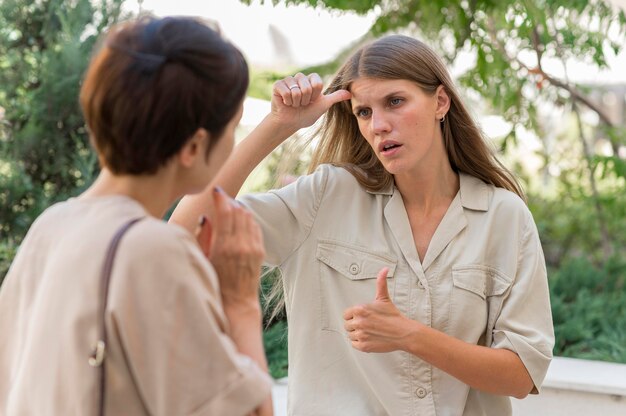 Dos amigas conversando al aire libre con lenguaje de señas